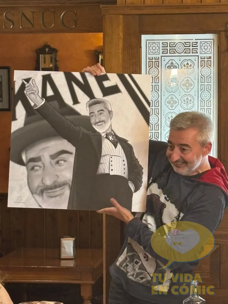 Fotografía real del homenajeado posando sonriente con la lámina personalizada que recibió como regalo de despedida de parte de sus compañeros de trabajo. Emoción, humor y arte hecho a mano.